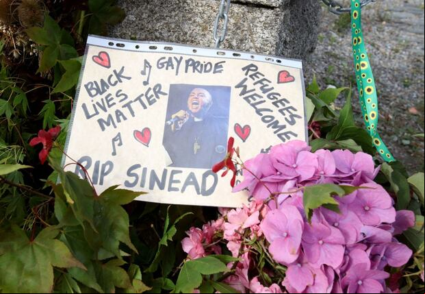 Las flores y los tributos se muestran fuera de la antigua casa de la cantante irlandesa Sinead O'Connor, en Bray, en el este de Irlanda, antes de su funeral el 8 de agosto de 2023 (Foto: Paul Faith / AFP)