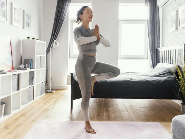 En esta imagen se aprecia a una mujer muy concentrada mientras realiza un ejercicio en casa. (Foto: Freepik)