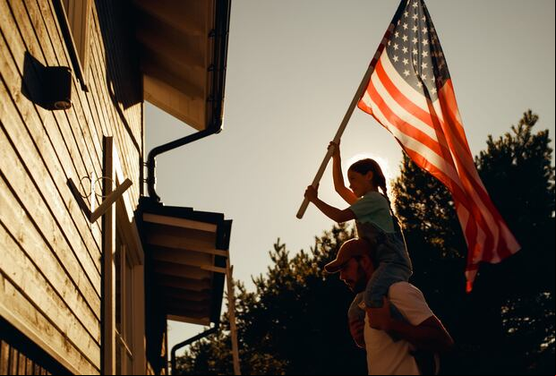 Una niña va a colocar una bandera de Estados Unidos en una vivienda. (Foto: gorodenkoff/iStock)